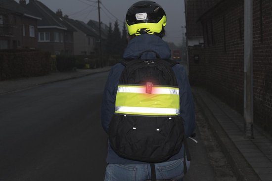 Rugzak met gele band en reflecterende strepen, gedragen door een persoon met helm.