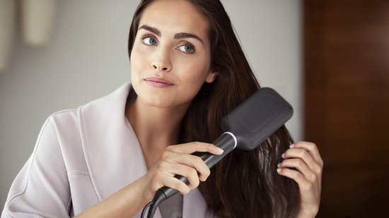 Vrouw met bruin haar gebruikt een zwarte Philips haarstijlborstel.
