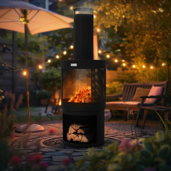Zwarte tuinhaard met vlammen en hout, in een tuin setting met verlichting.