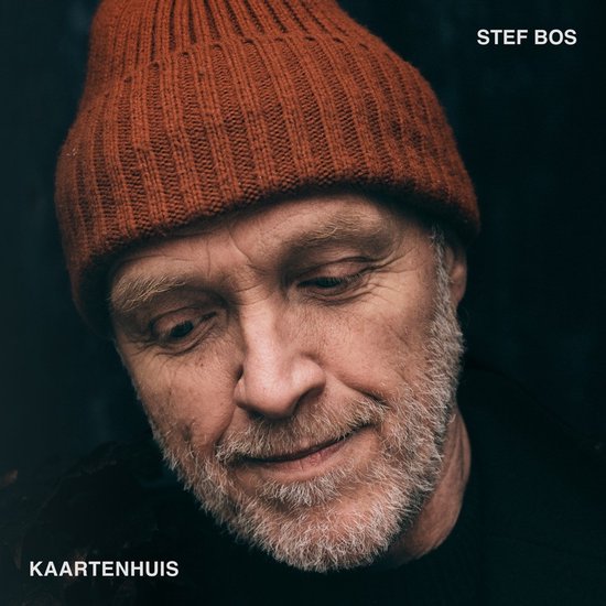 Stef Bos - Kaartenhuis, close-up van een man met oranje muts.