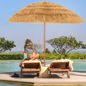 Man ontspant onder een strooien parasol bij een zwembad en de oceaan.