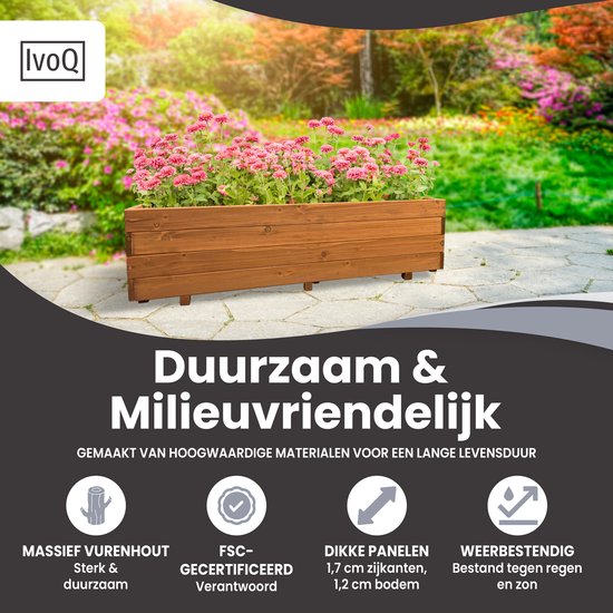 Houten plantenbak met roze bloemen op een steeg, omringd door groen.