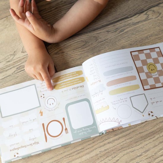 Kinderhand wijst naar een pagina in het vriendenboekje met tekeningen en invulvelden.
