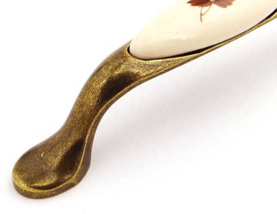 Messingkleurige kastgreep, detail van de gebogen poot met crème porselein en bruine bladeren.