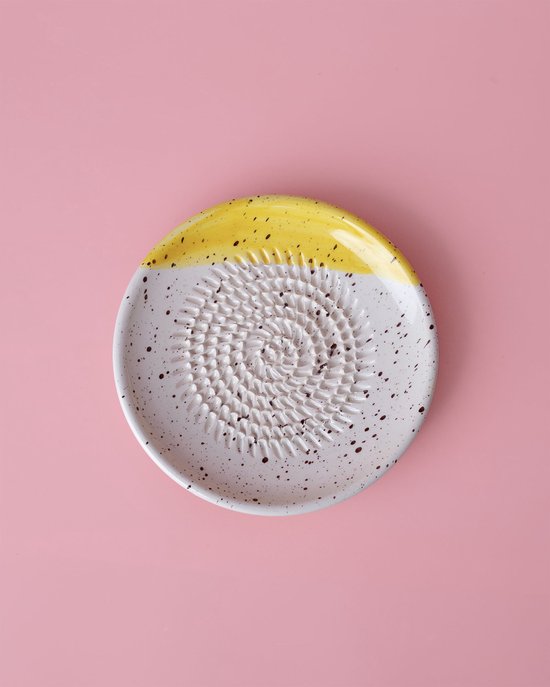 Petit bol râpe blanc avec dessus jaune et éclaboussures marron.