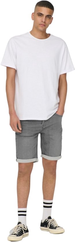Volledige outfit van een man in een witte t-shirt en grijze denim shorts, met gestreepte sokken.