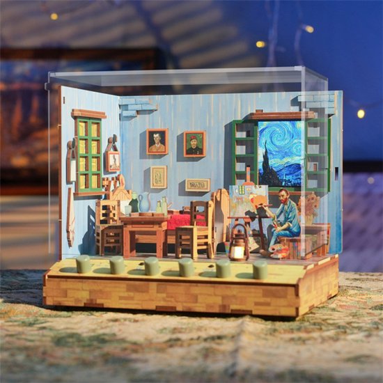 Diorama van een slaapkamer met schilder Vincent aan het werk, met meubels, schilderijen en een raam met Sterrennacht.