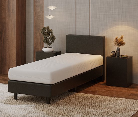 Zwarte boxspring met wit matras, vanuit een hoek bekeken.