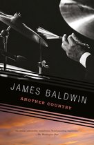 Boekcover van "Another Country" van James Baldwin. Een hand in pak houdt drumstokken vast boven een drumstel, met een zonsondergang op de achtergrond.