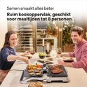 Een paar dat samen eet aan tafel met een contactgrill met steaks, groenten en gegrilde broodjes.