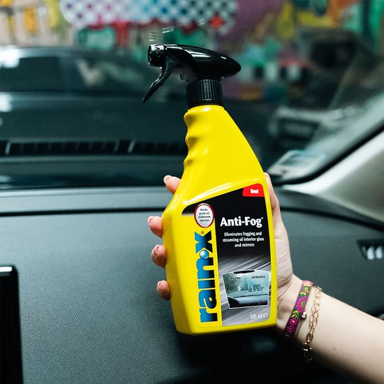 Gele Rain-X Anti-Damp sprayflacon in een hand. Tekst: "Nouveau! Nieuw!", "Rain-X", "Anti-Fog", "Eliminates fogging".