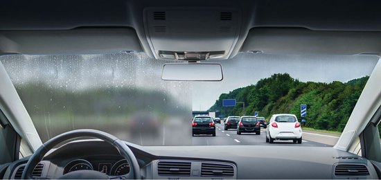 Zicht vanuit een auto op snelweg. Linkerruit beslagen, rechterruit helder. Tekst "TREATED" en "UNTREATED".