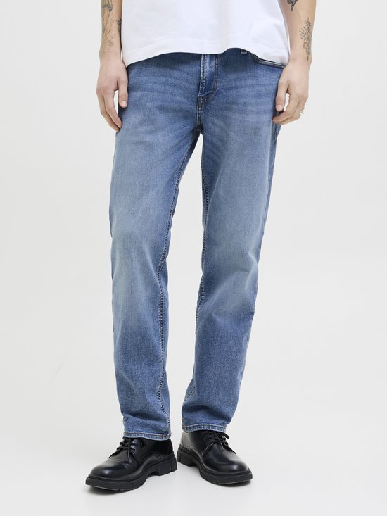 Model draagt een blauwe jeans met een witte t-shirt en zwarte schoenen.