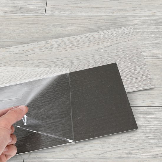 Hand pelt beschermfolie van een lichtgrijze vinyl vloerplank met houtnerf textuur.