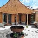 Een modern huis met een patio bedekt met bruine kokosvezel schaduwdoeken.