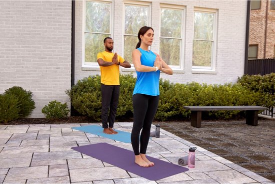 Vrouw met witte Garmin Vivosmart 5 doet yoga met een man buiten.