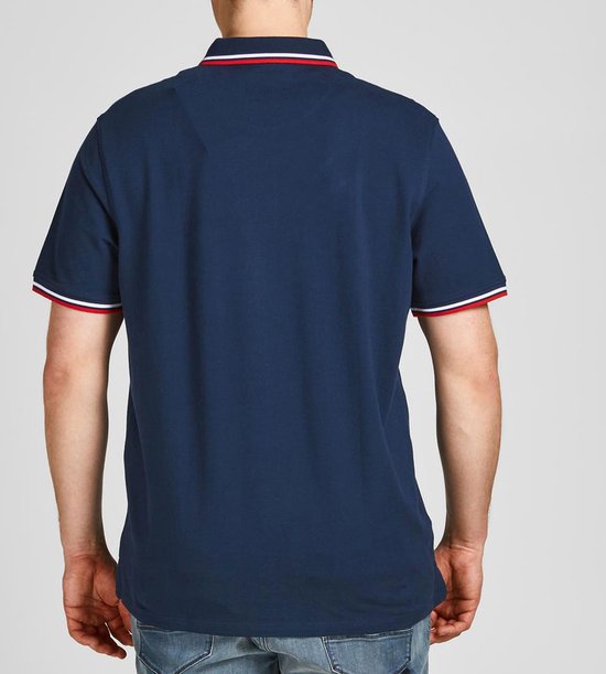 Achterkant van een donkerblauwe polo met rood-wit gestreepte kraag en mouwboorden. Man draagt jeans.