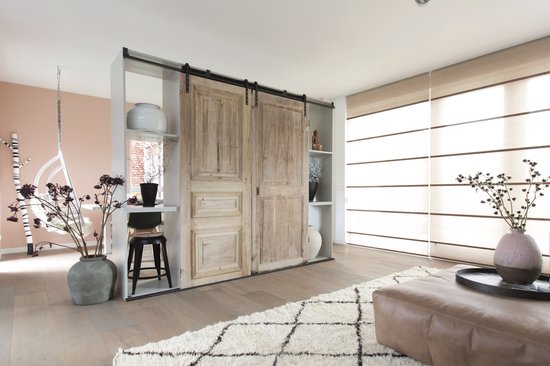 Moderne woonkamer met landelijke, houten schuifdeuren en een witte vloer.