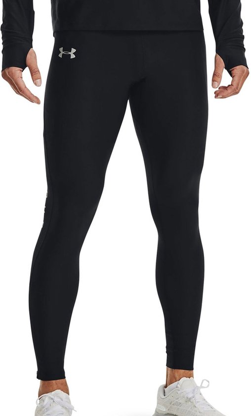 Man draagt zwarte Under Armour sportlegging met zilveren logo op linkerheup en witte sportschoenen.