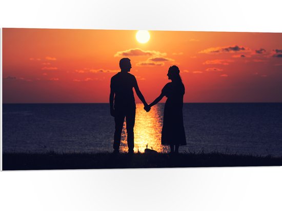 PVC Schuimplaat- Silhouet van Koppel Hand in Hand bij de Zee tijdens Zonsondergang - 100x50 cm Foto op PVC Schuimplaat