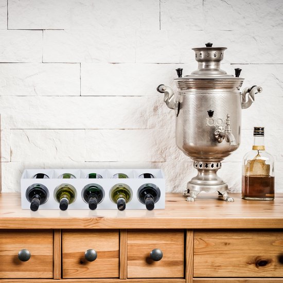 Wit wijnrek met 5 flessen op een houten dressoir, naast een grote zilveren samovar.