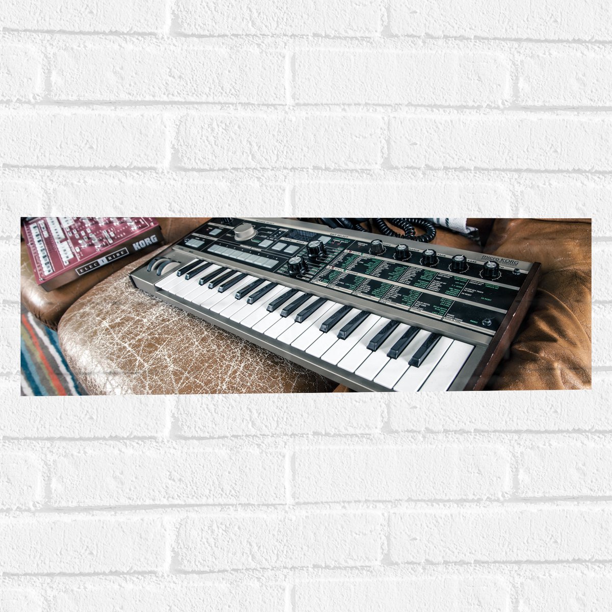 Muursticker - Oud Keyboard op Bruine Leren Bank - 60x20 cm Foto op Muursticker