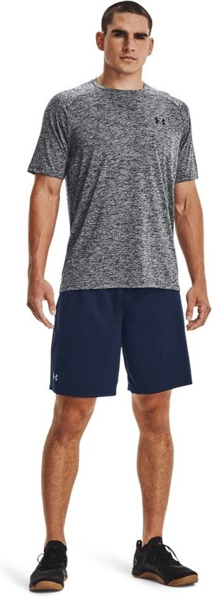 Man draagt een donkergrijs gemêleerd Under Armour sportshirt met korte mouwen en een donkerblauwe korte broek.