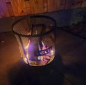 Brandende zwarte metalen vuurkorf met VOLT! logo, op een betegeld terras.