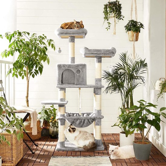 Grijze kattenkrabpaal met meerdere plateaus en hangmat, geplaatst op een balkon.