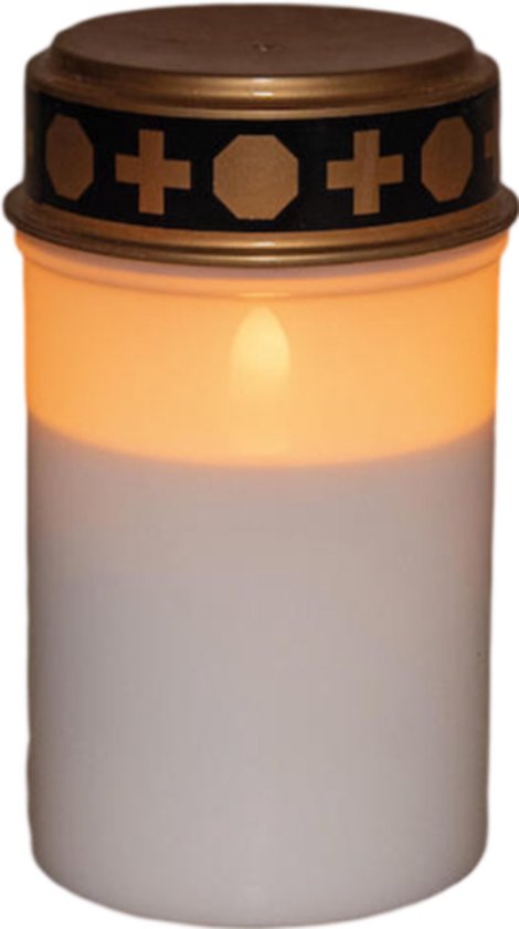 Bougie funéraire blanche avec couvercle doré et décoration en croix, s'allume d'une lueur chaude.
