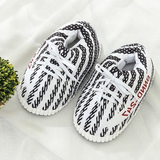 Bovenaanzicht van zwart-witte sneaker-pantoffels met veters op een witte ondergrond.