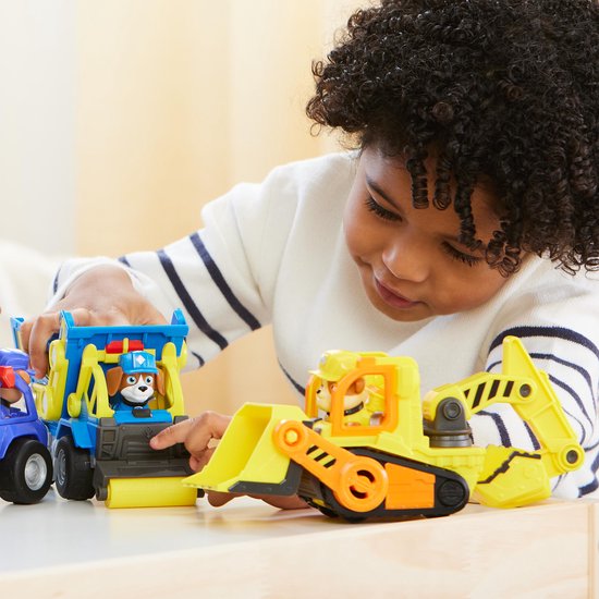 Jongen speelt met een blauwe kiepwagen en een gele graafmachine.