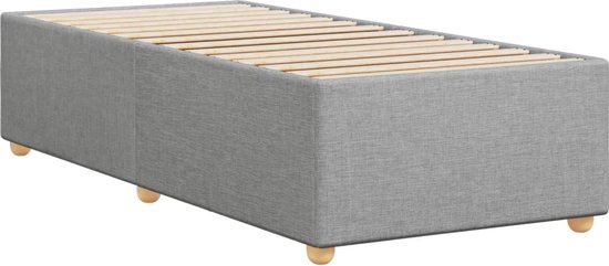 Cadre de lit gris clair en tissu avec sommier à lattes et courts pieds en bois, vu de trois quarts avant.