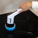 Hand houdt witte GoScrub elektrische schoonmaakborstel met blauwe opzetborstel op een zwarte kookplaat.