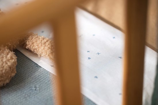 Detail van een wiegdeken met een wit katoenen deel met blauwe sterretjes en een grijs gebreid deel.