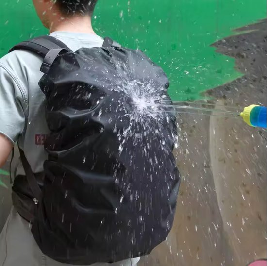 Man met zwarte rugzakhoes waarop water wordt gespoten.