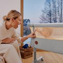 Vrouw speelt met baby in beige co-sleeper.