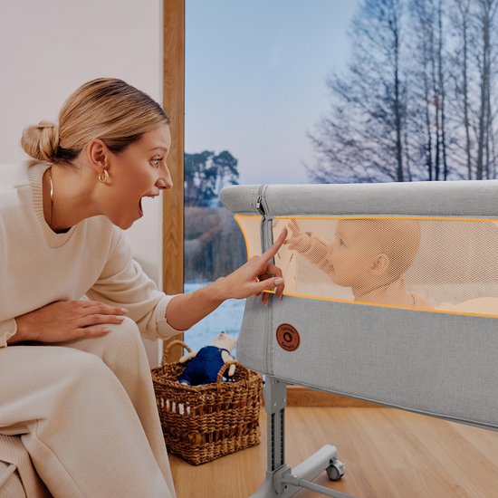 Vrouw speelt met baby in beige co-sleeper.