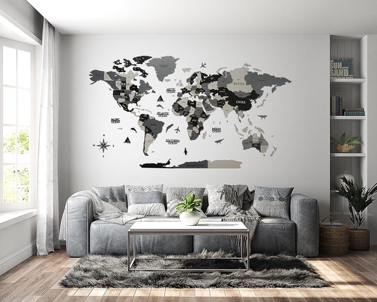 Carte du monde murale en bois grise et crème au-dessus d'un canapé gris dans un salon lumineux.