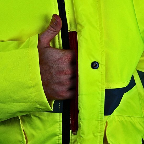 Buitenkant van een felgele jas met een rode rits aan de zijkant en grijze reflecterende details. Een hand in de zak.