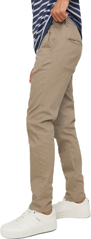 Man met gestreept blauw-wit T-shirt en beige chino broek, de zijkant zichtbaar.