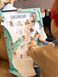 Een kind pakt een Sinterklaas ABC poster uit.