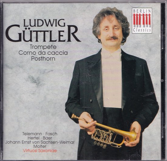 Ludwig Güttler, een man met grijzend krullend haar en snor, draagt een zwart pak met strik. Hij houdt een kleine gouden trompet vast.