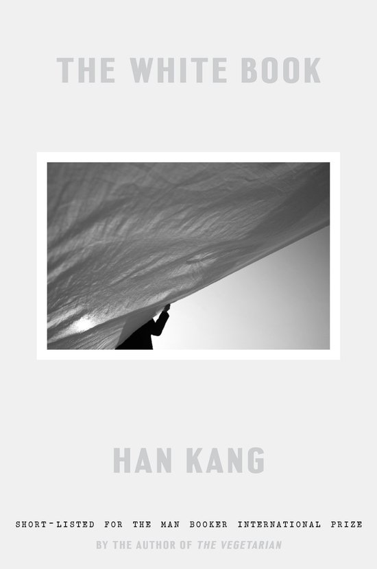 Het boek 'The White Book' van Han Kang, kort genomineerd voor de Man Booker International Prize. Grijze omslag met een foto van een persoon die een wit laken omhoog houdt.