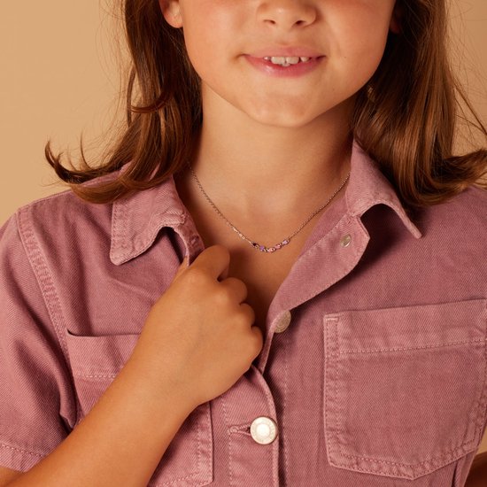 Zilverkleurige ketting met zes gekleurde emaille hartjes (paars, roze) gedragen door een meisje met roze shirt.