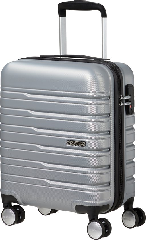 Zilveren koffer met ribbelstructuur, uitschuifbare handgreep, cijferslot en logo 'American Tourister'.