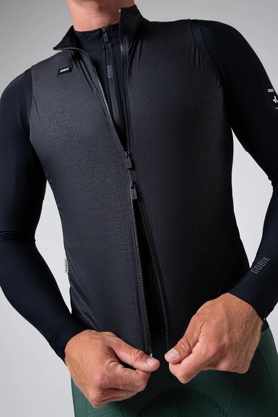 Detailopname van een zwart GOBIK fietsvest met rits over een zwart fietsshirt met lange mouwen.