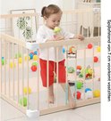 Houten babybox met gesloten hekjes. Een jong meisje drinkt uit een flesje. Spijlafstand 7 cm.