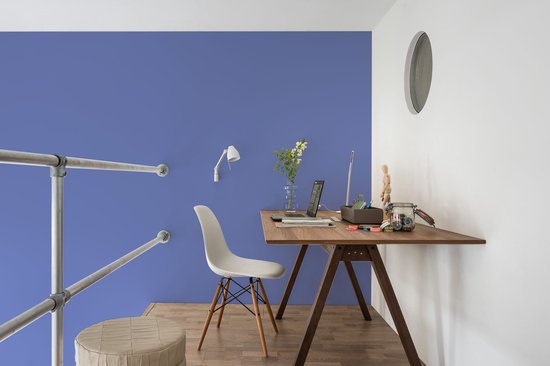 Werkplek aan huis met bureau, laptop en een blauwe muur.