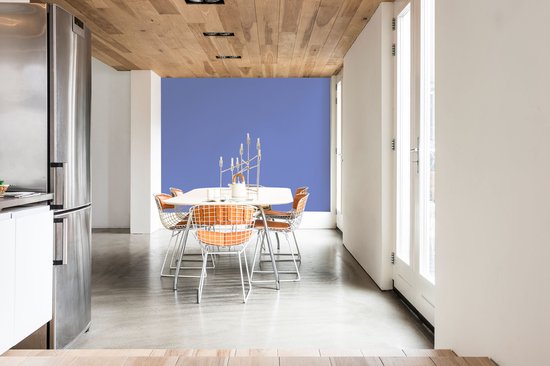 Eetkamer met eettafel, oranje stoelen en een blauwe muur.
